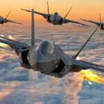 Four fighter jets flying above clouds, firing flares.