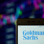 Phone displaying Goldman Sachs logo in front of chart