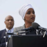 Two people speaking at a podium with microphones