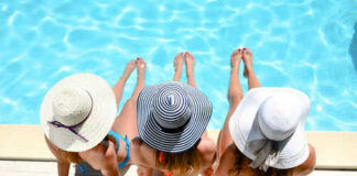 Three people in hats sitting by the pool