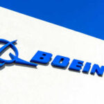 Boeing logo on a white building, blue sky.