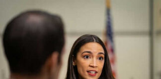 Person speaking to reporters with microphones indoors