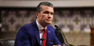 Man in suit sitting at a desk with microphone
