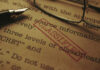 Close-up of a classified document with a pen and glasses