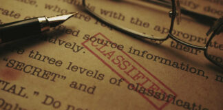 Close-up of a classified document with a pen and glasses