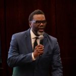 A man in a suit speaking into a microphone at a conference
