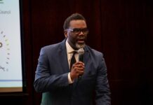 A man in a suit speaking into a microphone at a conference
