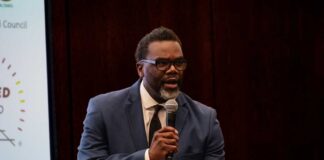 A man in a suit speaking into a microphone at a conference