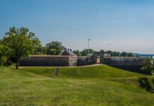 Historic fort with grassy landscape and trees under a clear blue sky