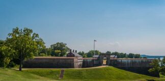 Historic fort with grassy landscape and trees under a clear blue sky