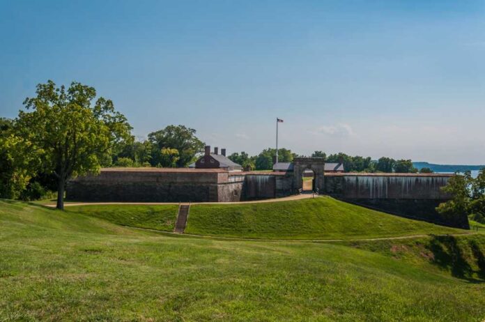 shutterstock_2262919977.jpg Historic fort with grassy landscape and trees under a clear blue sky