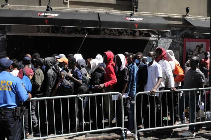 A crowd of people waiting in line outside a venue with a security officer present