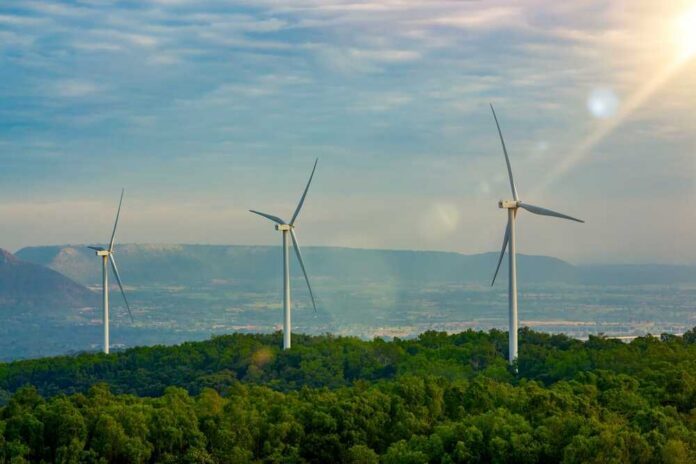 Three wind turbines on a green hillside under a cloudy sky
