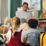 A teacher reading to a group of children sitting on the floor