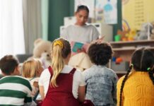 A teacher reading to a group of children sitting on the floor