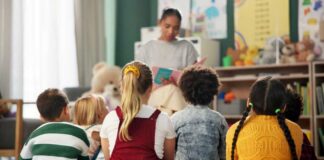 A teacher reading to a group of children sitting on the floor