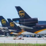 Three UPS cargo planes parked at an airport with visible tails