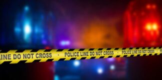 Police crime scene tape with emergency lights in the background