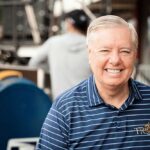 Smiling man in a striped shirt at an outdoor event