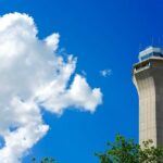 Burning Smell Grounds Flights: Newark in Chaos A tall airport control tower against a blue sky with clouds