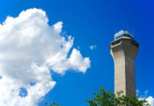 Burning Smell Grounds Flights: Newark in Chaos A tall airport control tower against a blue sky with clouds