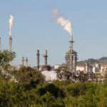 Industrial refinery with smoke stacks and flames against a clear sky