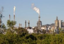 Industrial refinery with smoke stacks and flames against a clear sky