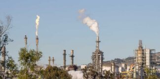 Industrial refinery with smoke stacks and flames against a clear sky
