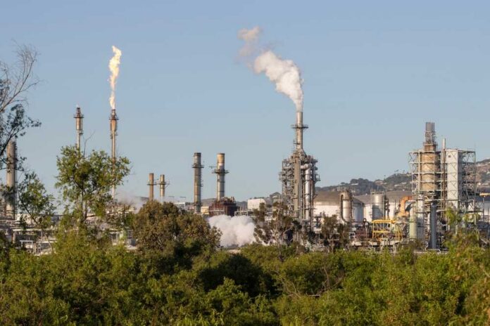 Industrial refinery with smoke stacks and flames against a clear sky