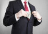 Businessman in a suit putting cash into his jacket pocket