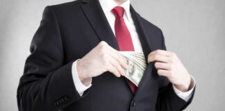 Businessman in a suit putting cash into his jacket pocket