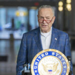 Man speaking at podium with United States emblem.