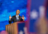 Man speaking at podium with blue starry background