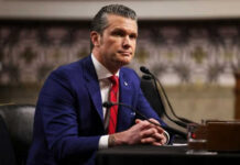 Man in blue suit speaking at a microphone