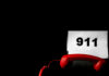A red telephone next to a paper displaying the number 911