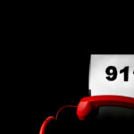A red telephone next to a paper displaying the number 911
