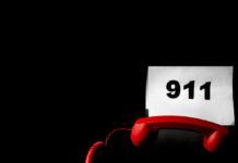 A red telephone next to a paper displaying the number 911