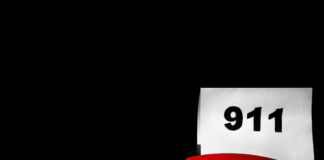A red telephone next to a paper displaying the number 911