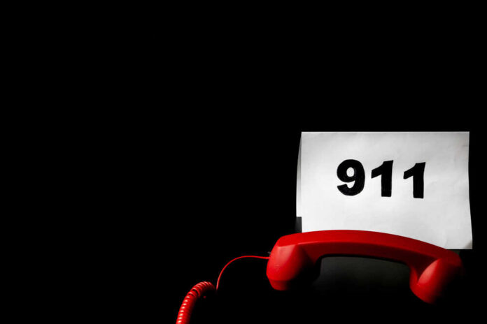 A red telephone next to a paper displaying the number 911