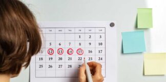 Person marking dates on a calendar with a red marker