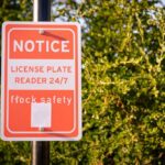 Notice sign indicating a 24/7 license plate reader for safety