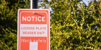 Notice sign indicating a 24/7 license plate reader for safety
