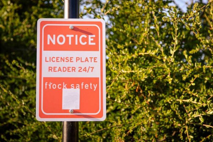 Notice sign indicating a 24/7 license plate reader for safety