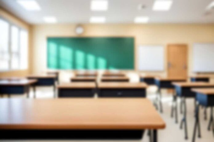 shutterstock_2475753311.jpg Empty classroom with desks, a green chalkboard, and natural light