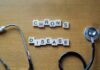 Wooden letter blocks spelling 'Crohn's Disease' next to a stethoscope