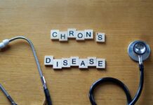 Wooden letter blocks spelling 'Crohn's Disease' next to a stethoscope
