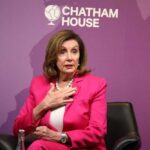 A woman in a pink suit speaking at a conference