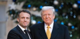 Two political leaders shaking hands in front of a decorated backdrop