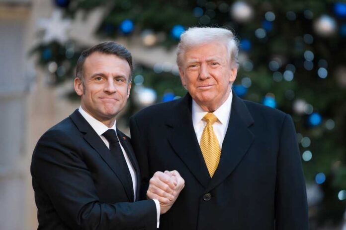 Two political leaders shaking hands in front of a decorated backdrop