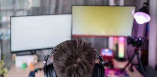 Person wearing headphones at a gaming setup with dual monitors